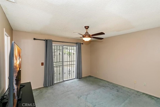 empty room featuring a ceiling fan, carpet, and a textured ceiling