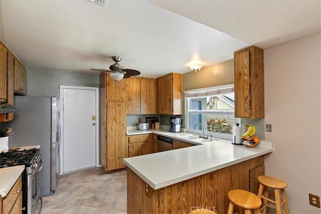 kitchen featuring a sink, light countertops, brown cabinetry, and stainless steel appliances