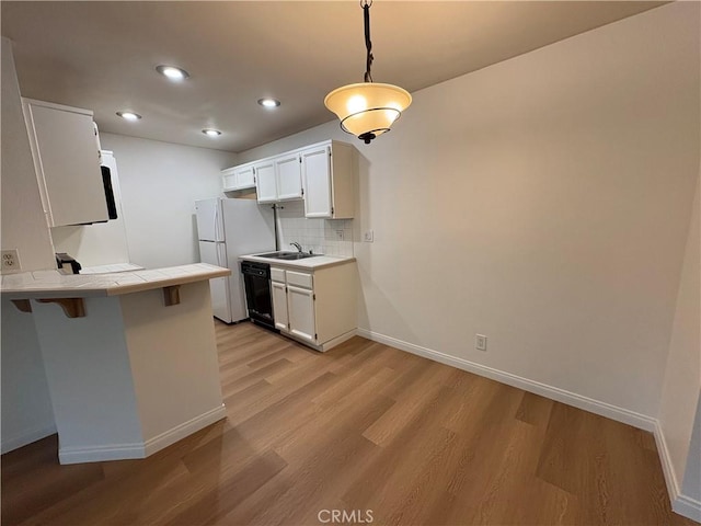 kitchen featuring baseboards, a peninsula, tile counters, black dishwasher, and recessed lighting