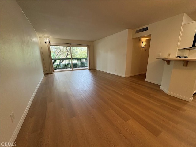 unfurnished living room with baseboards, wood finished floors, and visible vents