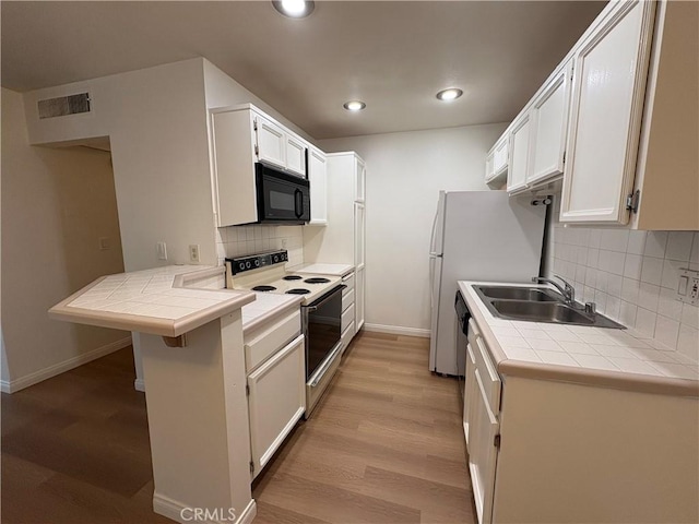 kitchen featuring electric range, black microwave, a sink, baseboards, and visible vents