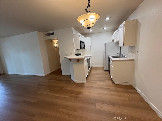 kitchen featuring range with electric stovetop, visible vents, black microwave, light countertops, and baseboards