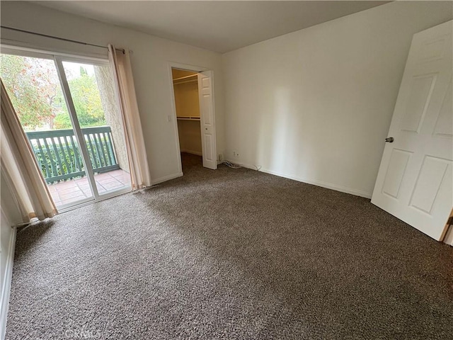 unfurnished bedroom featuring a closet, baseboards, access to outside, a spacious closet, and carpet