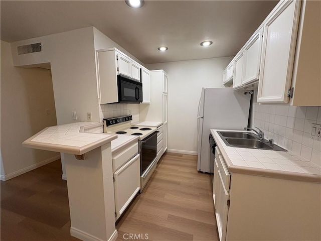 kitchen with white electric range oven, black microwave, a sink, baseboards, and visible vents