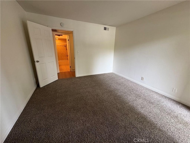 carpeted spare room featuring baseboards and visible vents