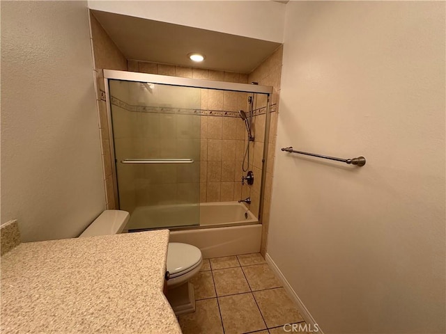 bathroom with tile patterned flooring, bath / shower combo with glass door, baseboards, and toilet