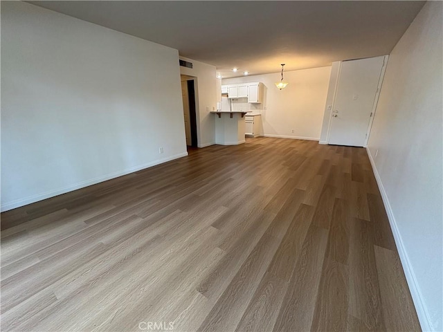 unfurnished living room with baseboards, wood finished floors, and visible vents