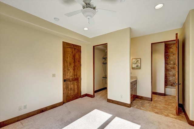unfurnished bedroom with baseboards, ensuite bathroom, a walk in closet, light colored carpet, and recessed lighting