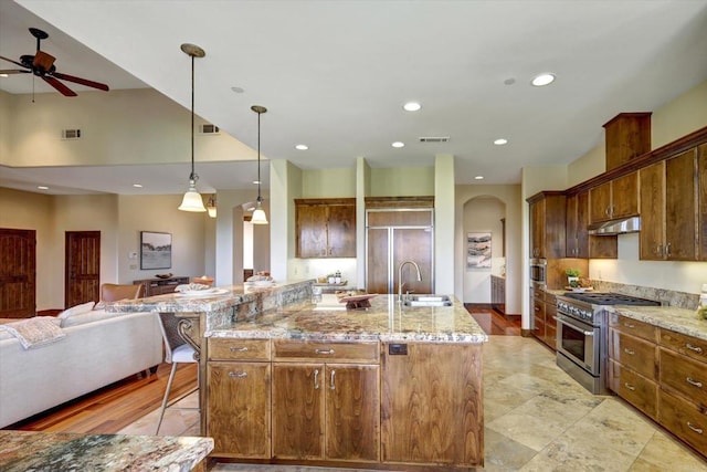 kitchen with a sink, arched walkways, open floor plan, premium appliances, and visible vents