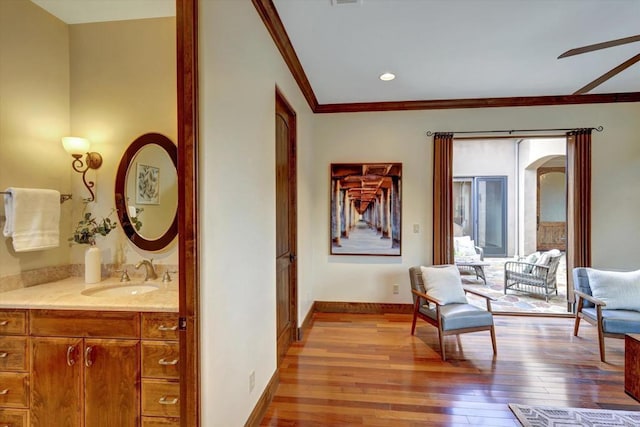 sitting room with arched walkways, ornamental molding, wood-type flooring, and baseboards