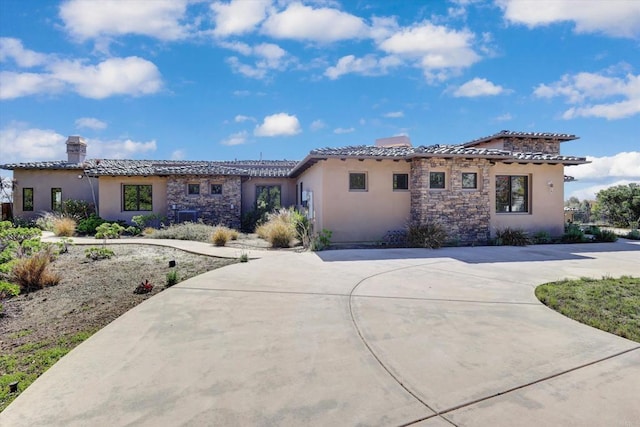 view of front of home featuring a chimney, stucco siding, a tiled roof, and stone siding