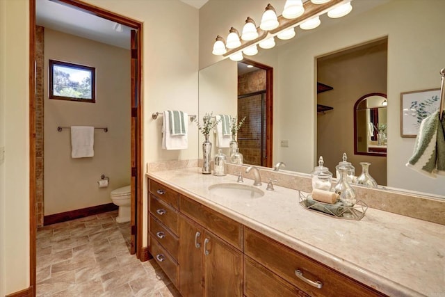bathroom with toilet, baseboards, and vanity