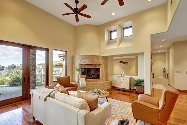 living room with ceiling fan, wood-type flooring, and a high ceiling