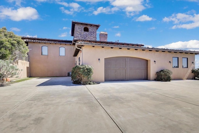 mediterranean / spanish home featuring driveway, a chimney, a tile roof, and stucco siding