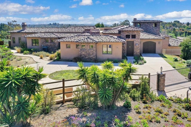 mediterranean / spanish home with a tiled roof, driveway, a chimney, fence private yard, and stucco siding