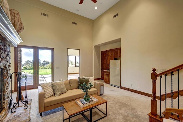 living area featuring visible vents, stairs, ceiling fan, and light colored carpet