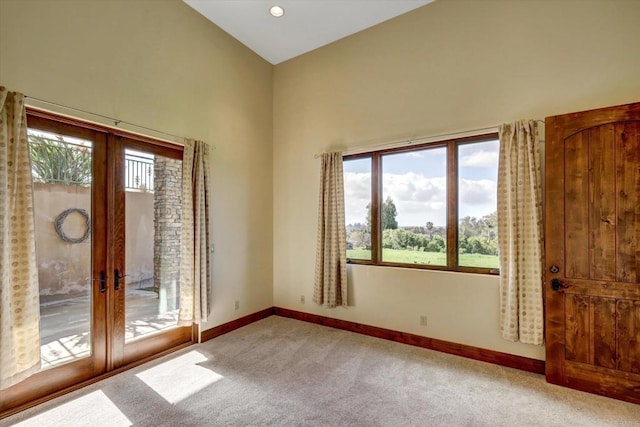 empty room featuring carpet flooring, baseboards, plenty of natural light, and french doors