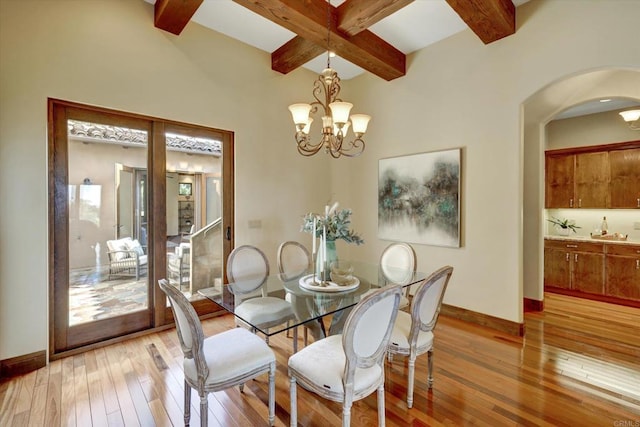 dining room with an inviting chandelier, arched walkways, baseboards, light wood-type flooring, and beamed ceiling