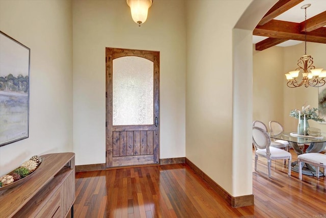 entrance foyer featuring arched walkways, baseboards, dark wood finished floors, and a chandelier
