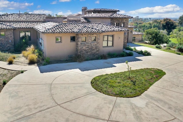view of home's exterior featuring stucco siding, a tile roof, and stone siding