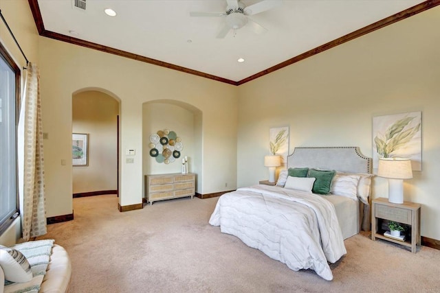 carpeted bedroom featuring crown molding, arched walkways, baseboards, and ceiling fan