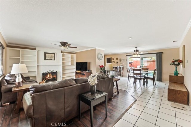14901 Quill Cir, Huntington Beach, CA 92647 - living area with ceiling fan, ornamental molding, a warm lit fireplace, and light tile patterned floors