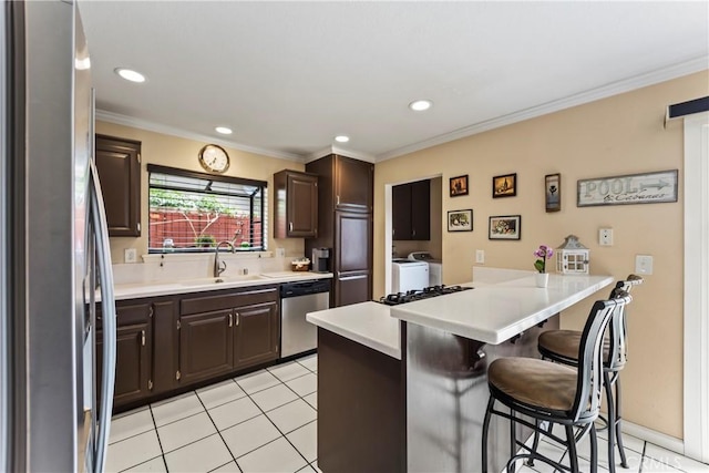 14901 Quill Cir, Huntington Beach, CA 92647 - kitchen with stainless steel appliances, separate washer and dryer, a peninsula, a breakfast bar, and dark brown cabinetry