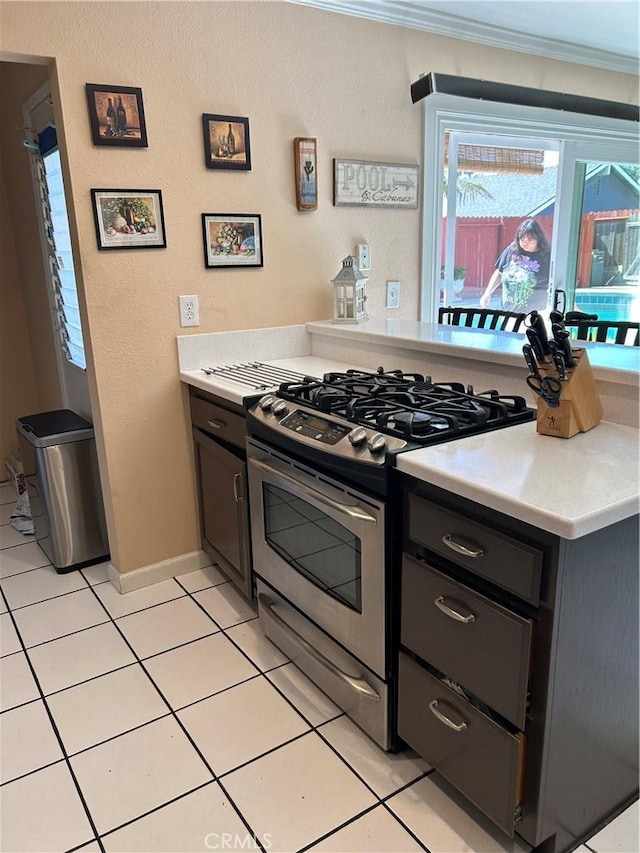 14901 Quill Cir, Huntington Beach, CA 92647 - kitchen with gas stove, light countertops, light tile patterned floors, ornamental molding, and baseboards