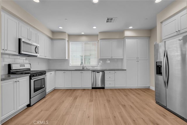 kitchen featuring visible vents, white cabinetry, a sink, backsplash, and stainless steel appliances