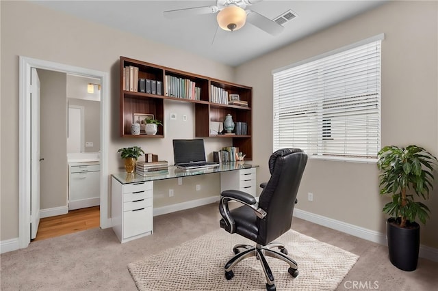 office featuring visible vents, a ceiling fan, baseboards, and light carpet