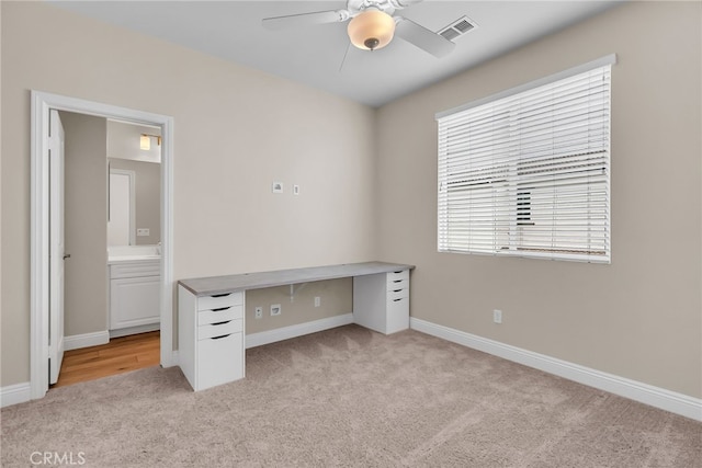 unfurnished office with ceiling fan, light colored carpet, baseboards, and visible vents