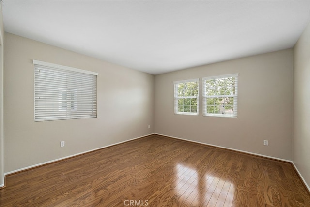 unfurnished room featuring baseboards and dark wood-type flooring