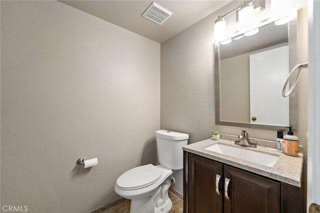 half bath featuring vanity, toilet, tile patterned floors, baseboards, and visible vents