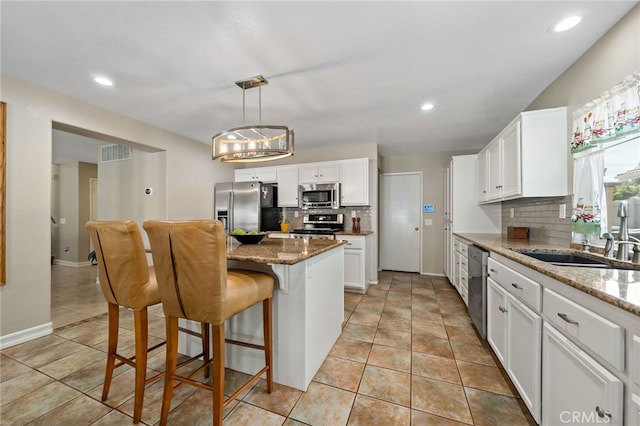 kitchen with tasteful backsplash, stainless steel appliances, white cabinetry, and visible vents