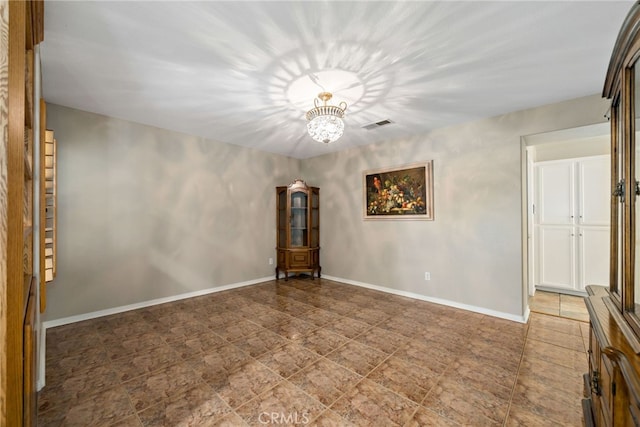 empty room featuring a notable chandelier, visible vents, and baseboards