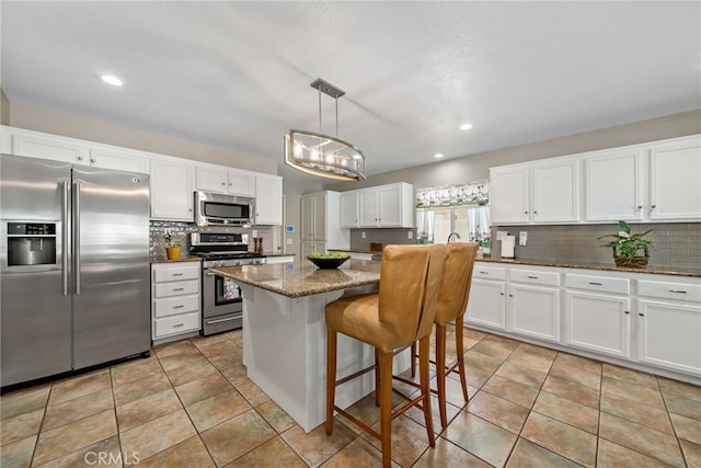 kitchen featuring a center island, white cabinetry, dark stone countertops, backsplash, and stainless steel appliances