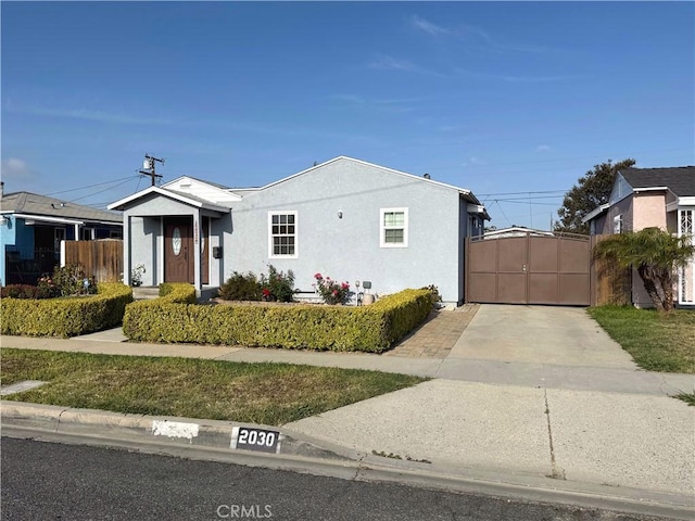view of front facade featuring stucco siding, a gate, and fence