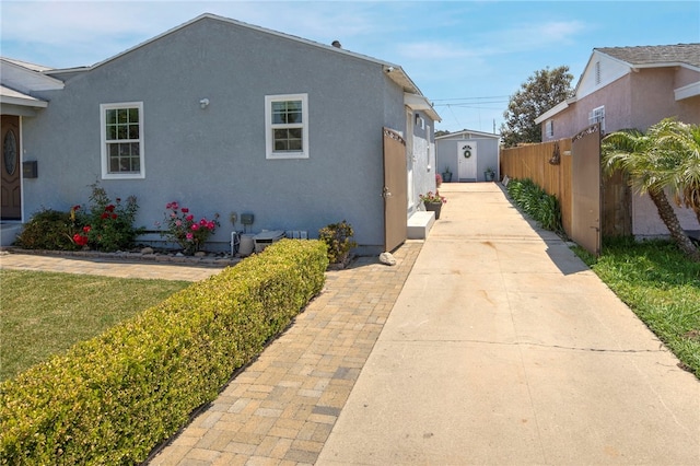2030 N Keene Ave, Compton, CA 90059 - view of home's exterior with driveway, a storage unit, stucco siding, fence, and an outbuilding