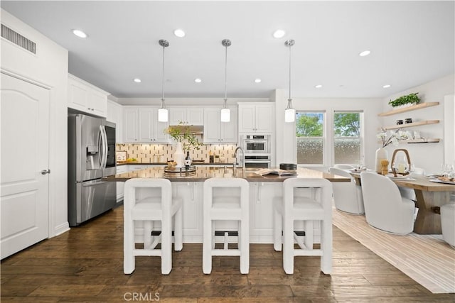 3040 E Coalinga Dr, Brea, CA 92821 - kitchen featuring appliances with stainless steel finishes, a kitchen breakfast bar, tasteful backsplash, white cabinets, and dark wood-type flooring