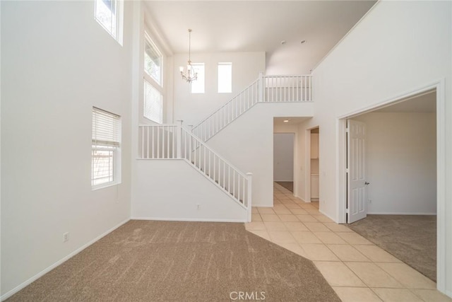 41044 Oak Creek Rd, Murrieta, CA 92562 - unfurnished living room featuring carpet, stairs, a chandelier, a high ceiling, and tile patterned flooring