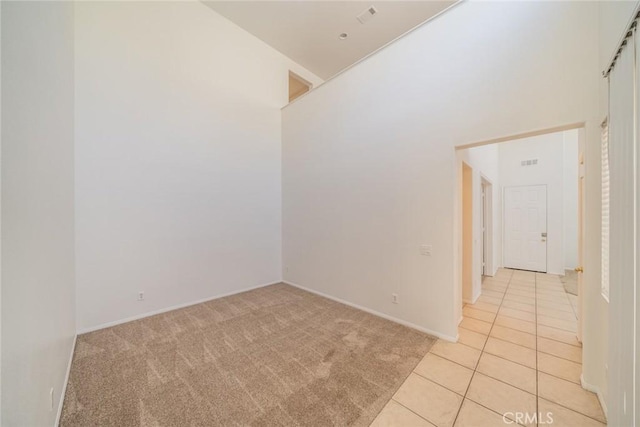 41044 Oak Creek Rd, Murrieta, CA 92562 - spare room featuring light tile patterned floors, light carpet, a high ceiling, and baseboards