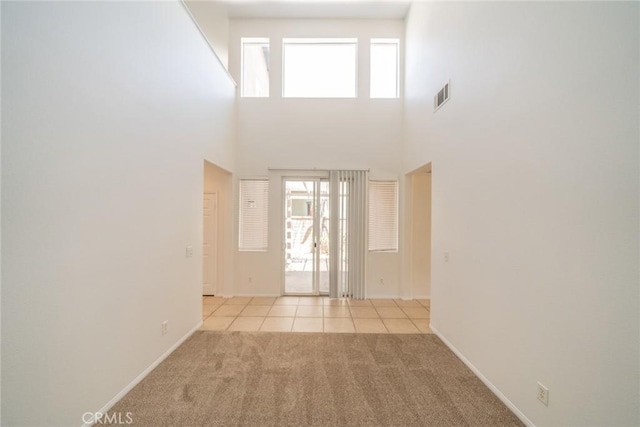 41044 Oak Creek Rd, Murrieta, CA 92562 - empty room with healthy amount of natural light, light colored carpet, light tile patterned floors, a towering ceiling, and baseboards