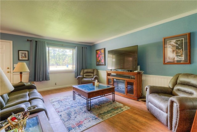 living area with crown molding, a wainscoted wall, a fireplace, and wood finished floors