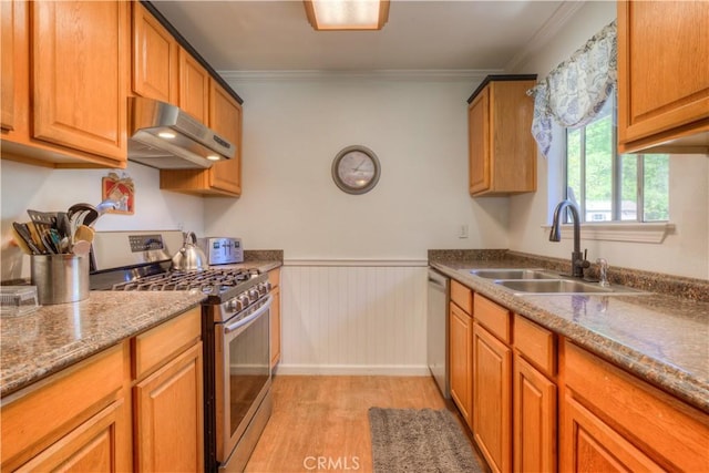 kitchen featuring crown molding, light wood-type flooring, a sink, under cabinet range hood, and stainless steel appliances