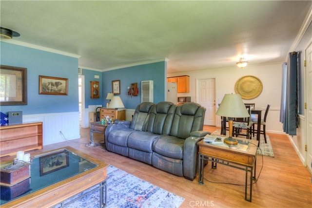 living room with ornamental molding, light wood-style flooring, and a wainscoted wall