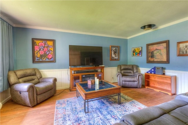 living area featuring ornamental molding, wood finished floors, and a wainscoted wall