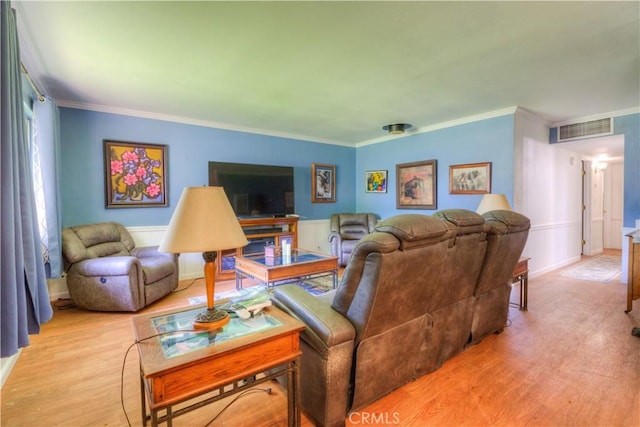 living area featuring crown molding, visible vents, a wainscoted wall, and light wood-type flooring