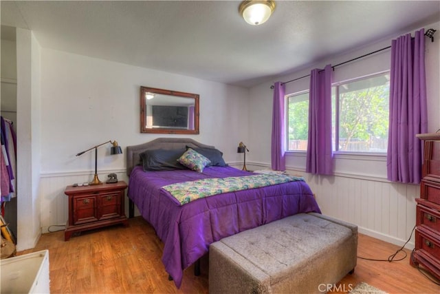 bedroom with wainscoting and wood finished floors