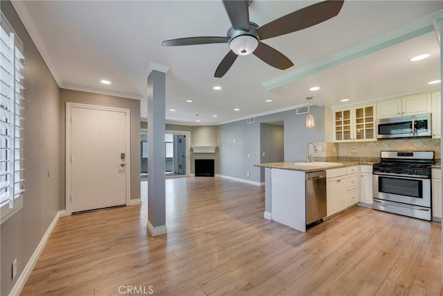 kitchen with stainless steel appliances, a sink, a peninsula, backsplash, and glass insert cabinets