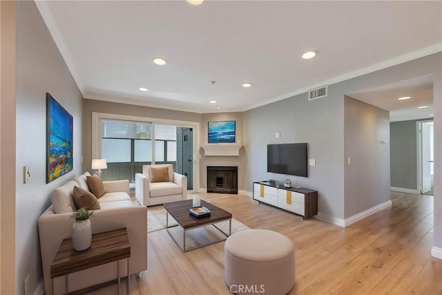 living area featuring a fireplace, crown molding, baseboards, light wood-type flooring, and recessed lighting